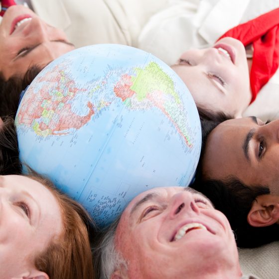 Multi-ethnic business people lying on the floor around a terrestrial globe