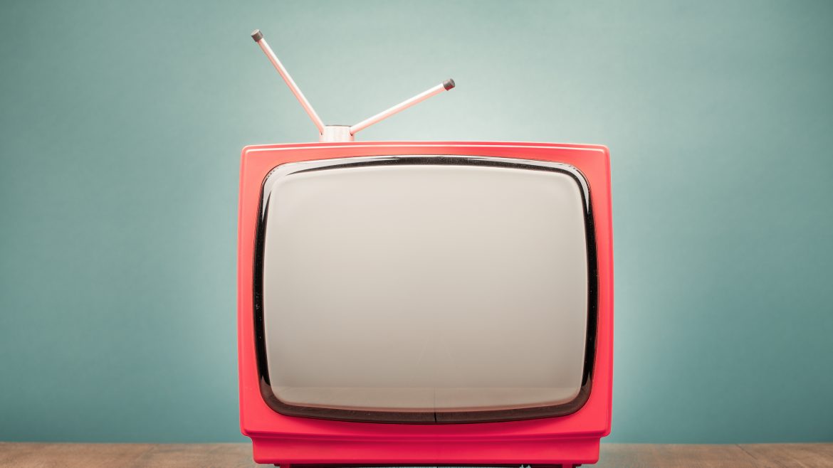 téléviseur rétro rouge avec une antenne devant un mur menthe